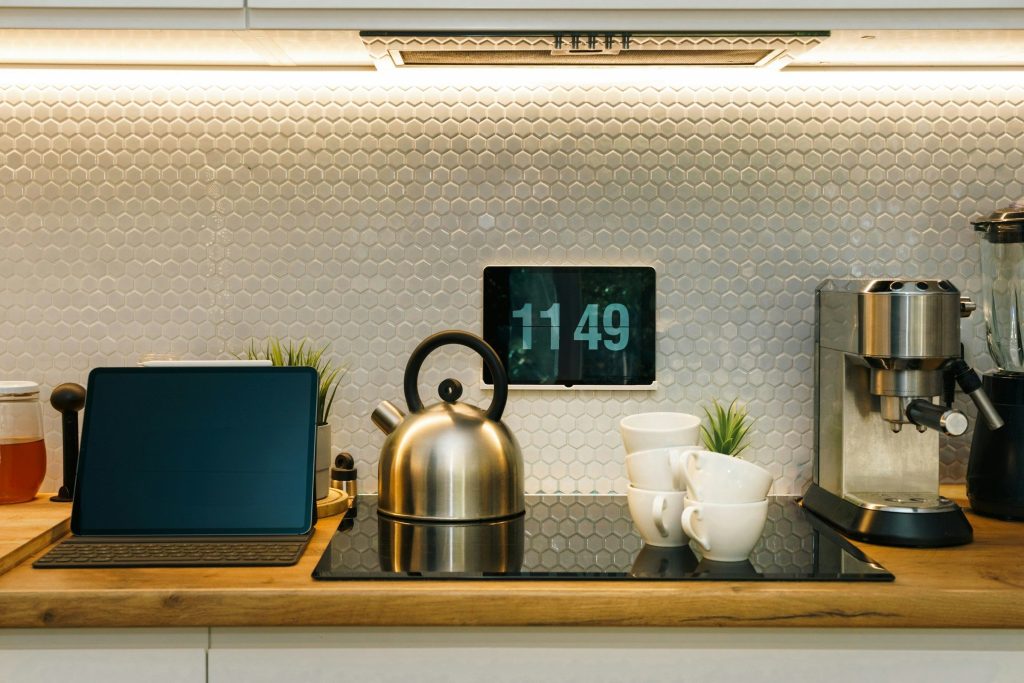 A worktop with an induction hob, a kettle on it, a tablet and a coffee machine either side, hexagon tile behind.