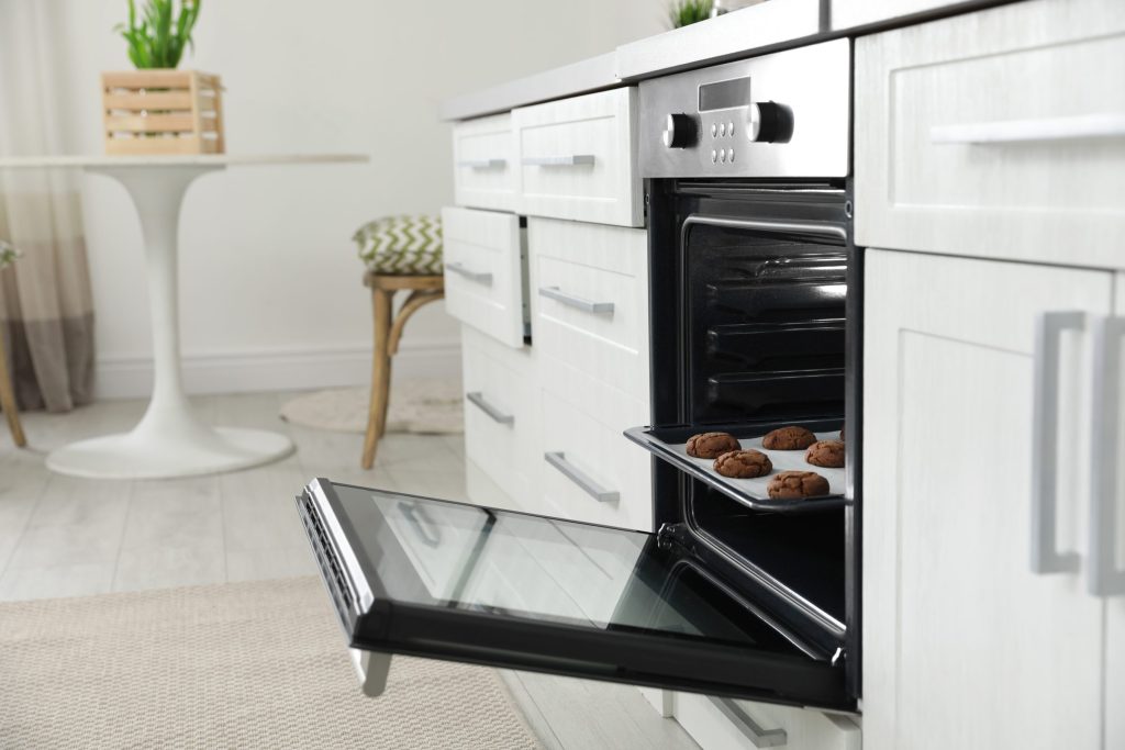 A tray of baked cookies on the open door of a wall oven.