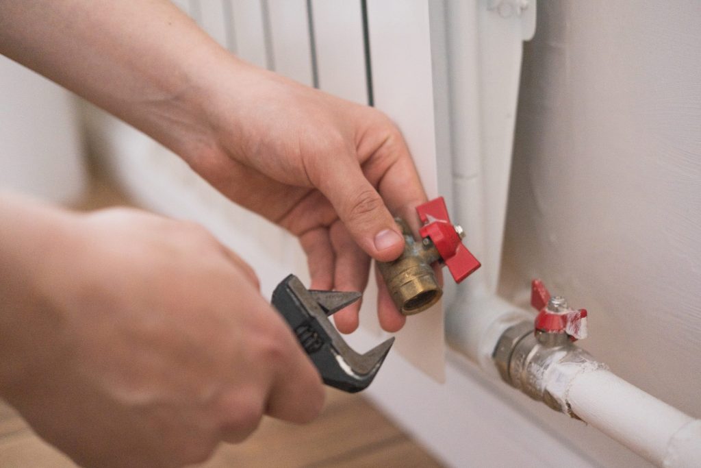 Hands fitting a brass gas valve to a pipe with an adjustable wrench