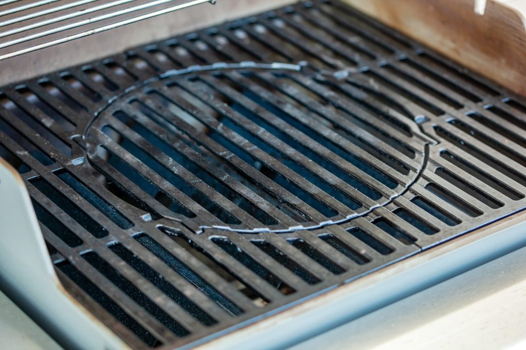 Cast grill grates with a rotisserie ring resting across them, close up