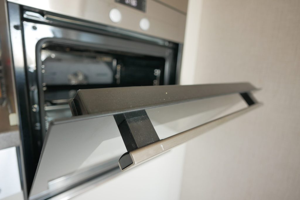 A built-in oven with the door part open, seen along the handle