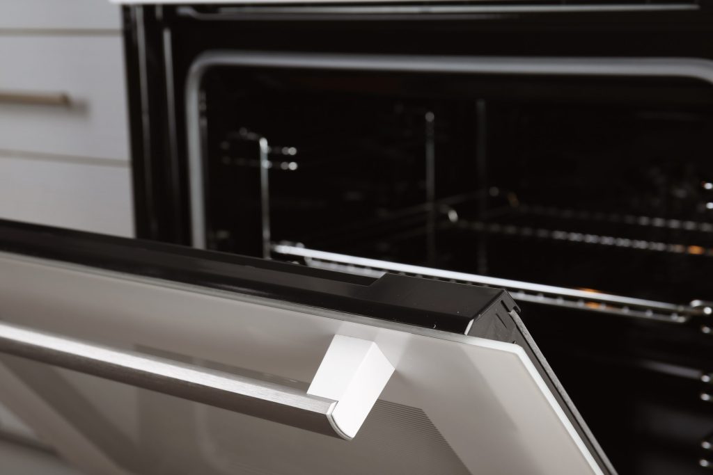 The door of a built-in oven standing ajar, racks visible inside