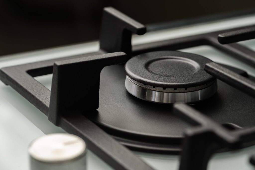 A sealed gas burner and cast grate on a dark cooking deck, close up