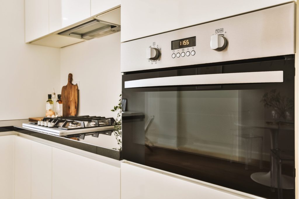 A gas hob beside a built-in oven in a white kitchen run