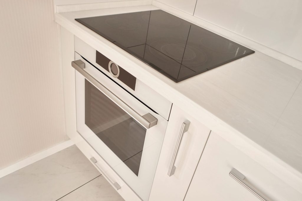 A black ceramic hob set into a white counter above a built-in oven