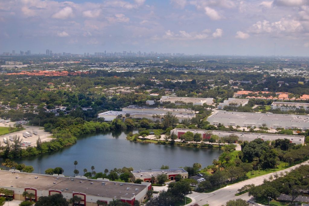 A lake and low buildings with a distant skyline beyond, from the air