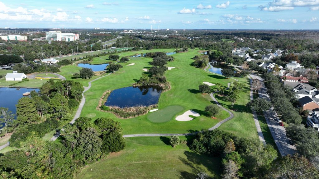 Golf fairways and water threading between houses, from the air