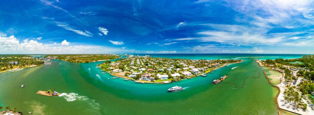 A turquoise inlet with an island of houses and moored boats, from the air