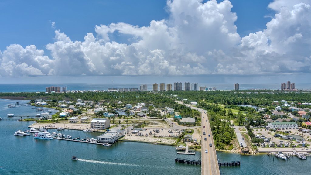 A causeway and marina with a row of towers along the beach behind
