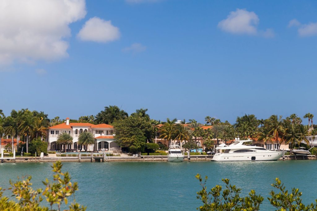 A row of waterfront houses with a yacht moored in front of them