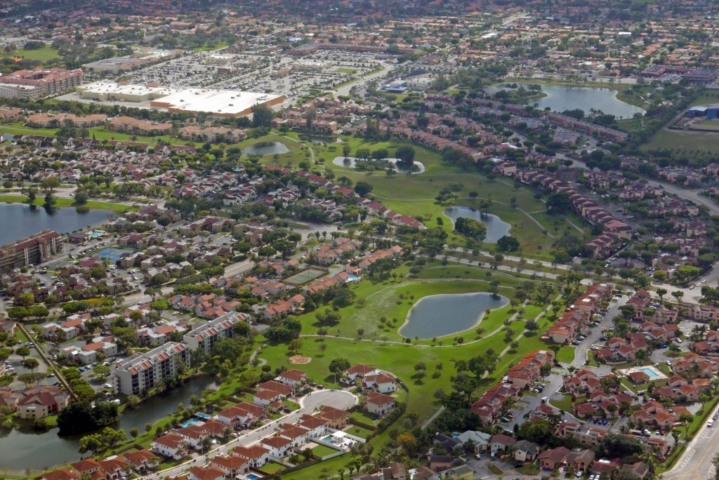 A wide residential district threaded with golf and lakes, from the air