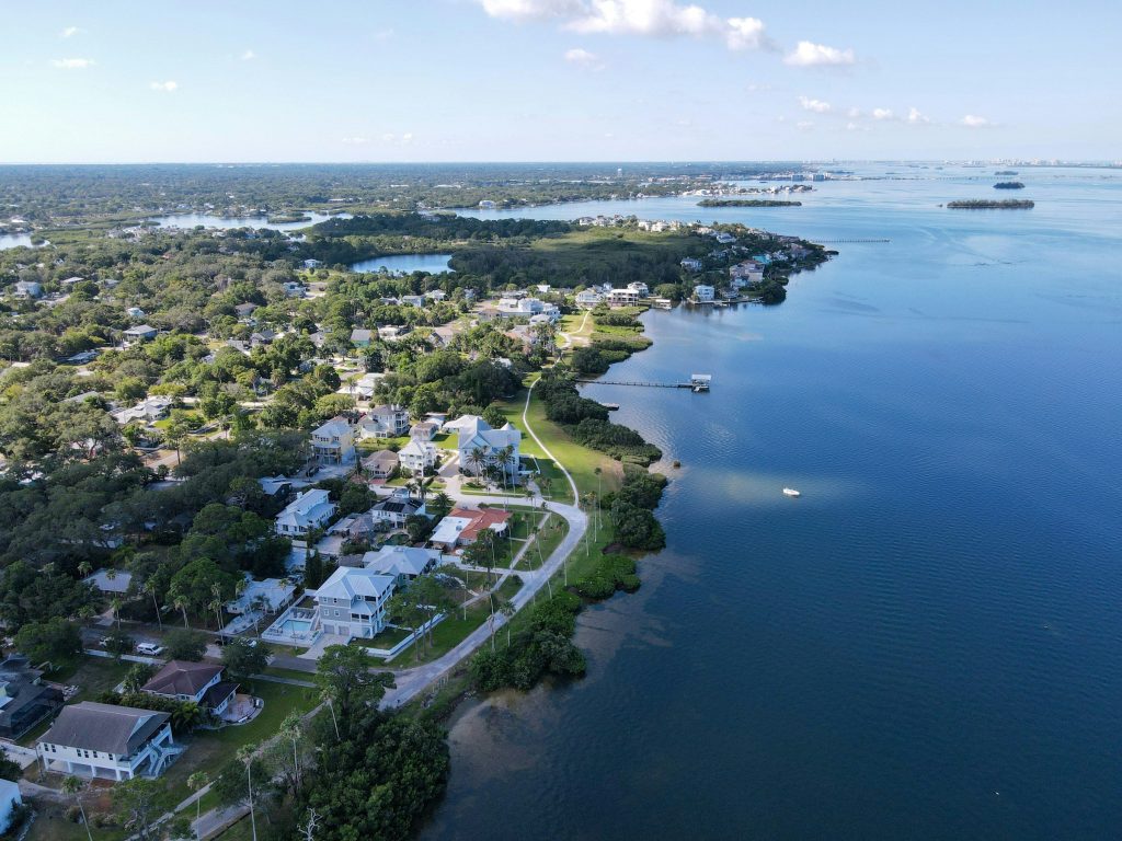 Houses among trees along a wide shoreline, from the air