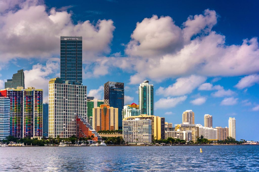 A skyline of towers seen across open water under cloud