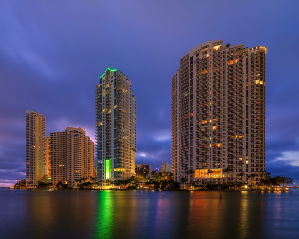Two lit towers reflected in still water before dawn