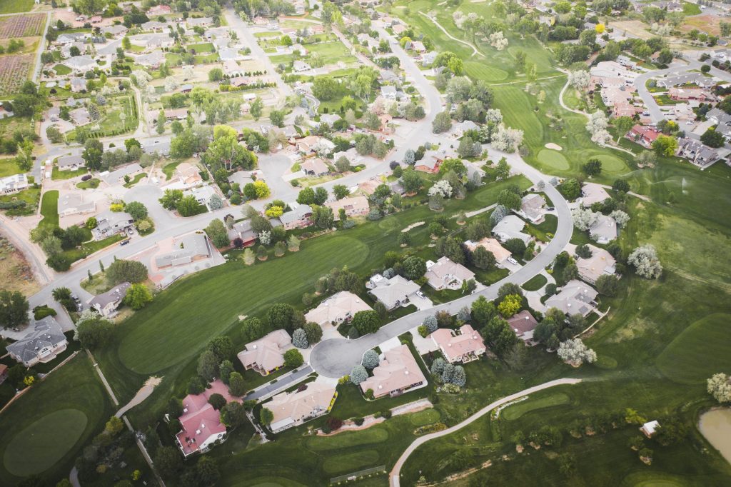 A suburb of houses wrapped around fairways and open green, from the air