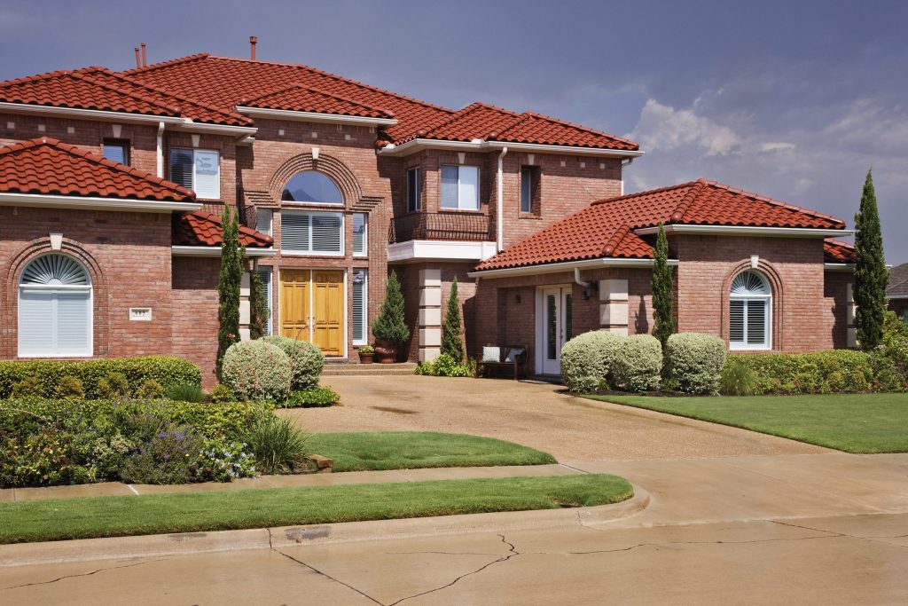 A large house with a red tile roof and a curving drive