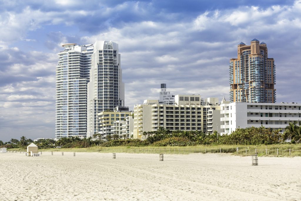 Tall condo towers seen from the sand along a curving shore