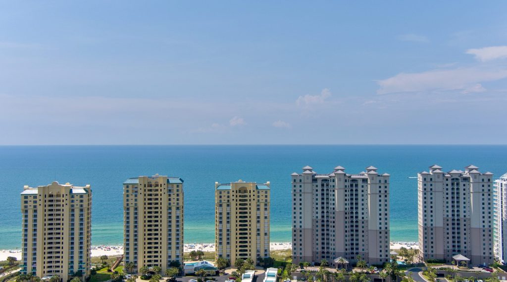 A line of tall condo towers above a beach and shallow water