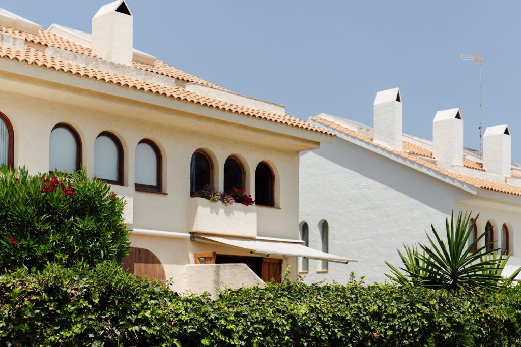 A white Mediterranean building with arched windows and planting below