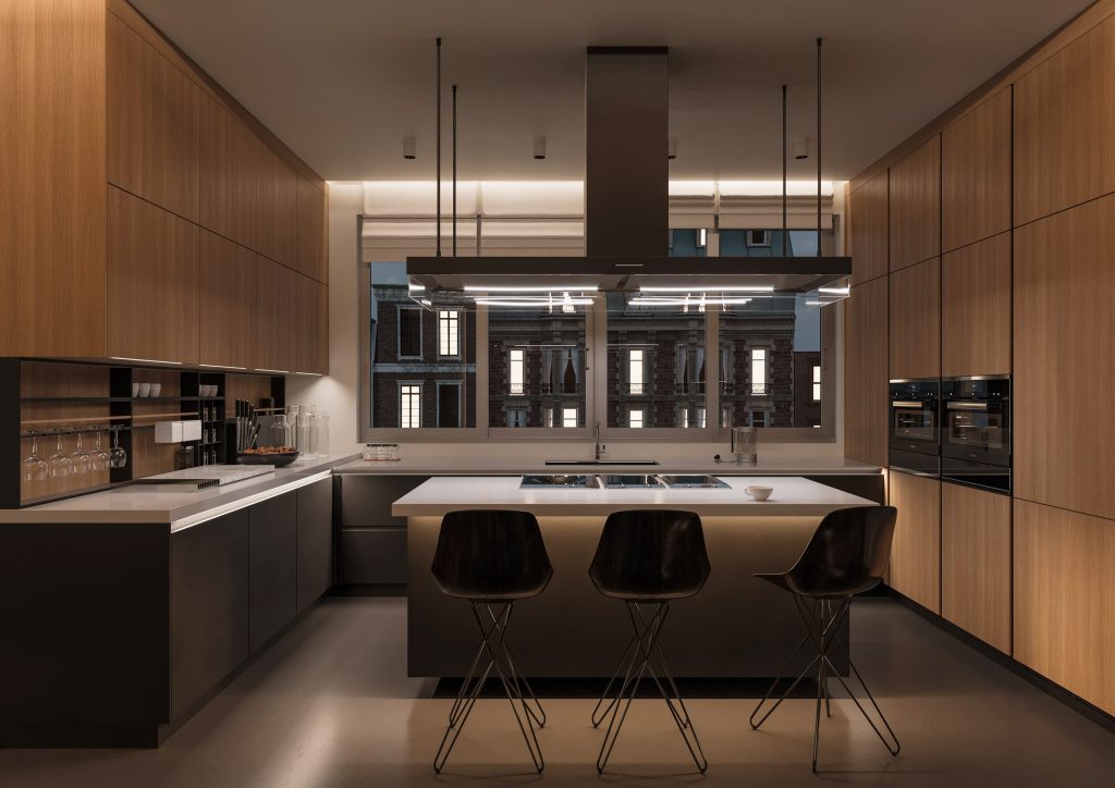A walnut-panelled kitchen at night, an island with three stools under a linear hood and a city window behind.