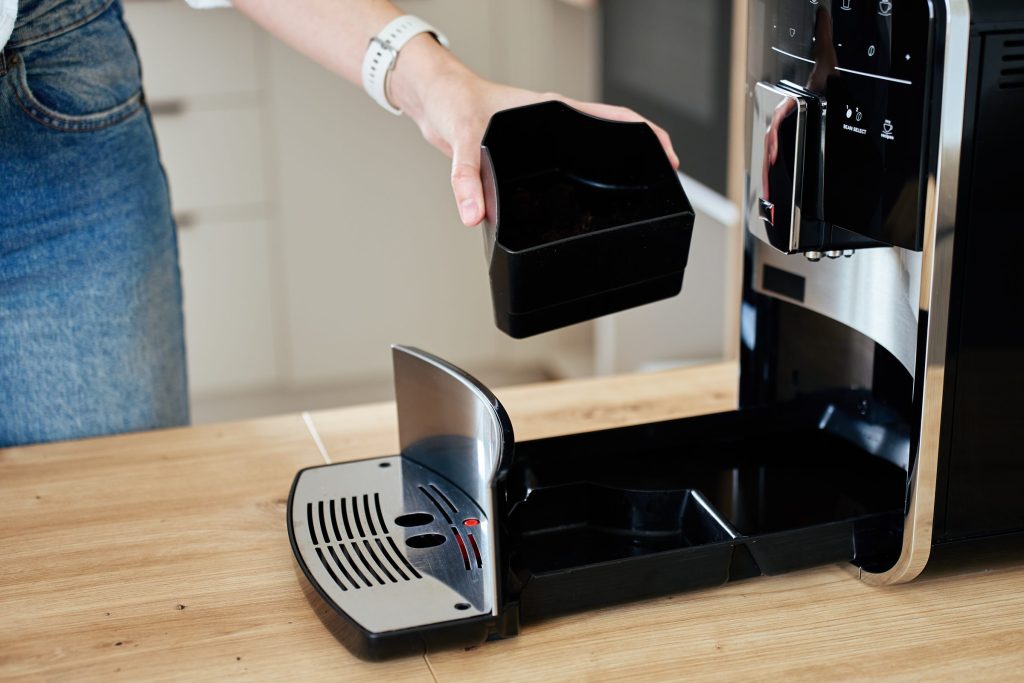 Someone wiping down the brew unit area of an automatic coffee machine