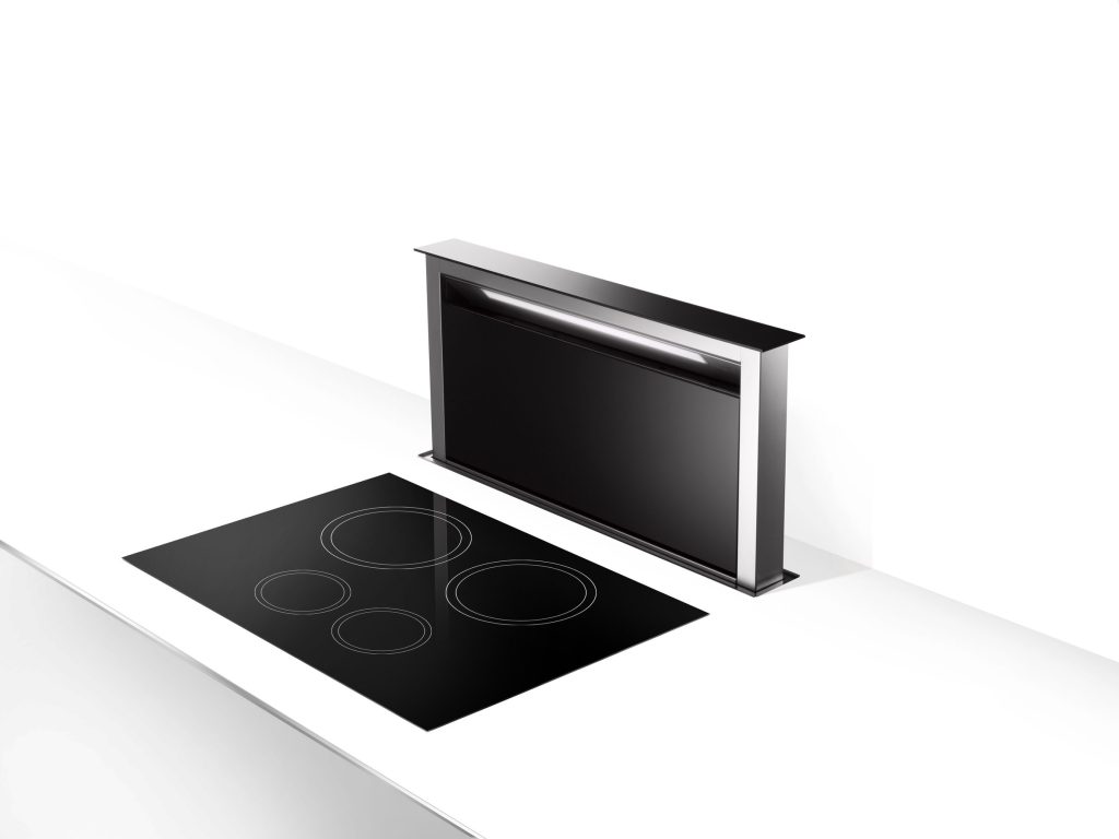 A downdraft vent raised out of the worktop behind a black cooktop
