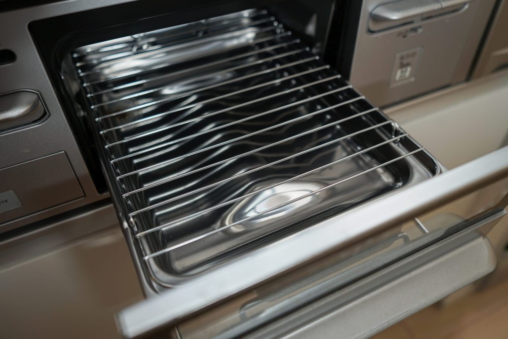 A broiler drawer pulled out of a range, its rack sitting over the drip pan