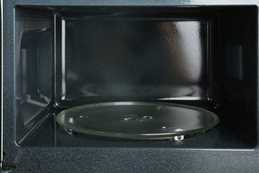 The inside of an open microwave, the glass turntable sitting on its roller ring