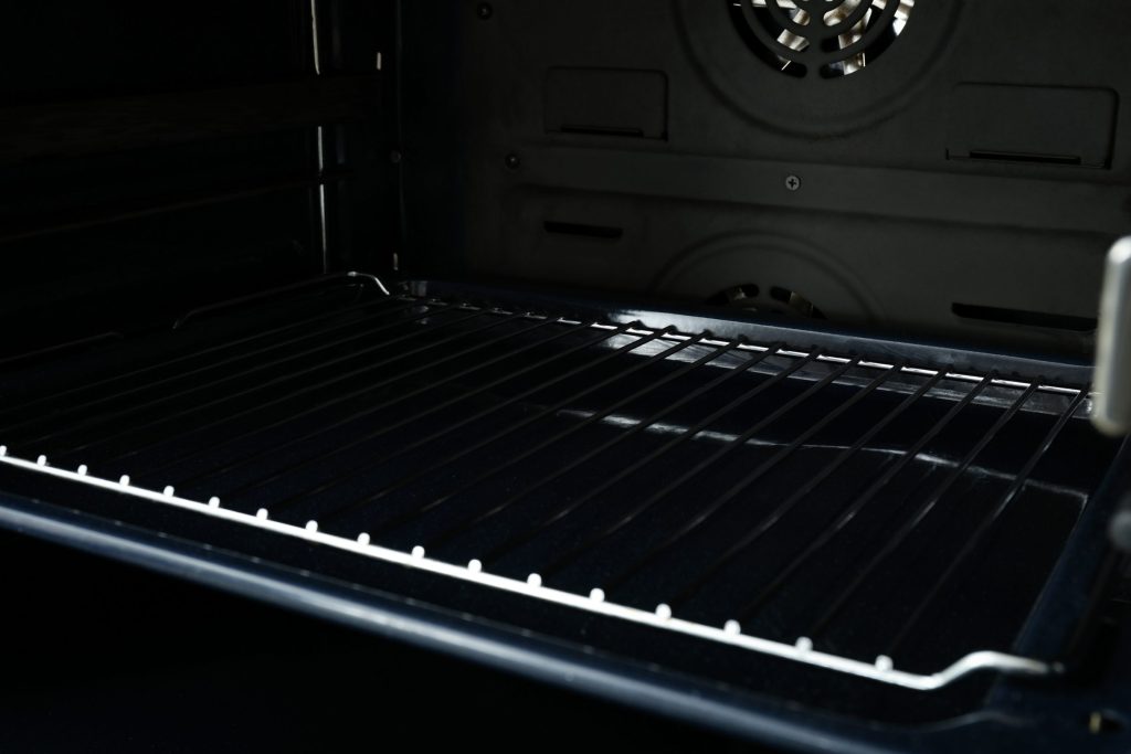 The inside of an unlit oven — one rack, the fan cover and the element housing at the back.