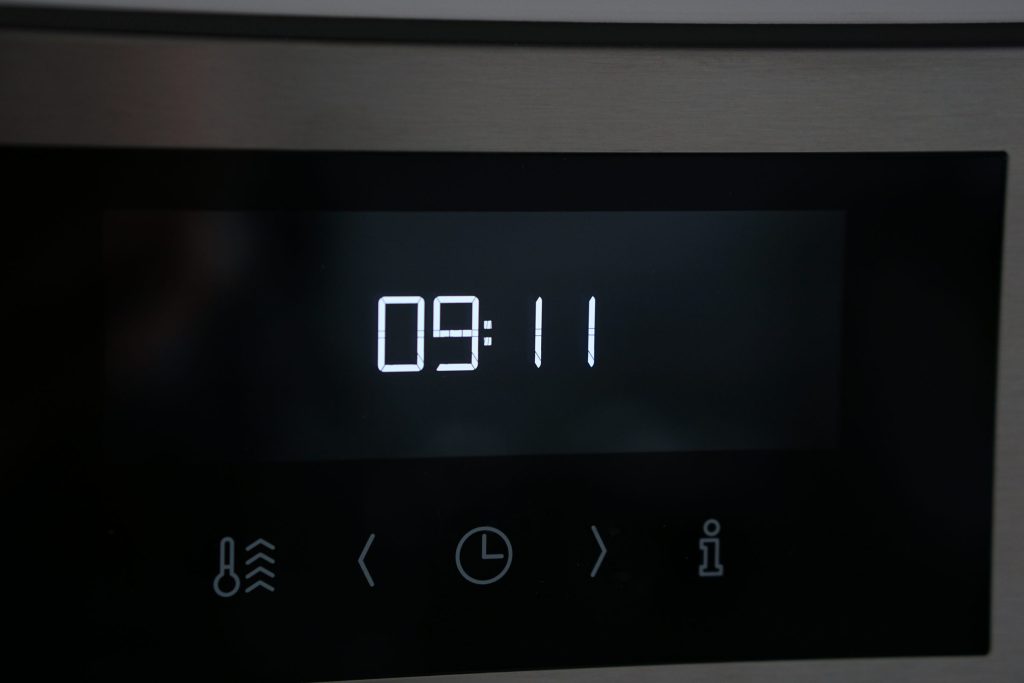The touch panel of a stainless oven, the clock reading 09:11 above five symbols.