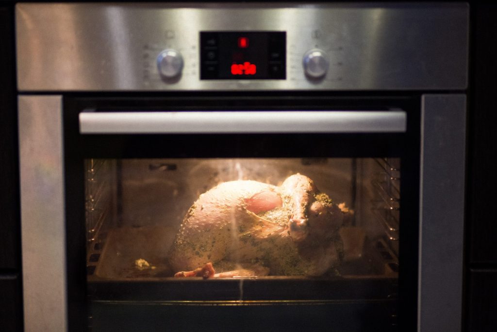 A built-in oven with a red segment display lit above the door, a roast inside