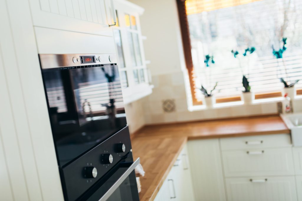 A black oven set under the counter in a bright kitchen.